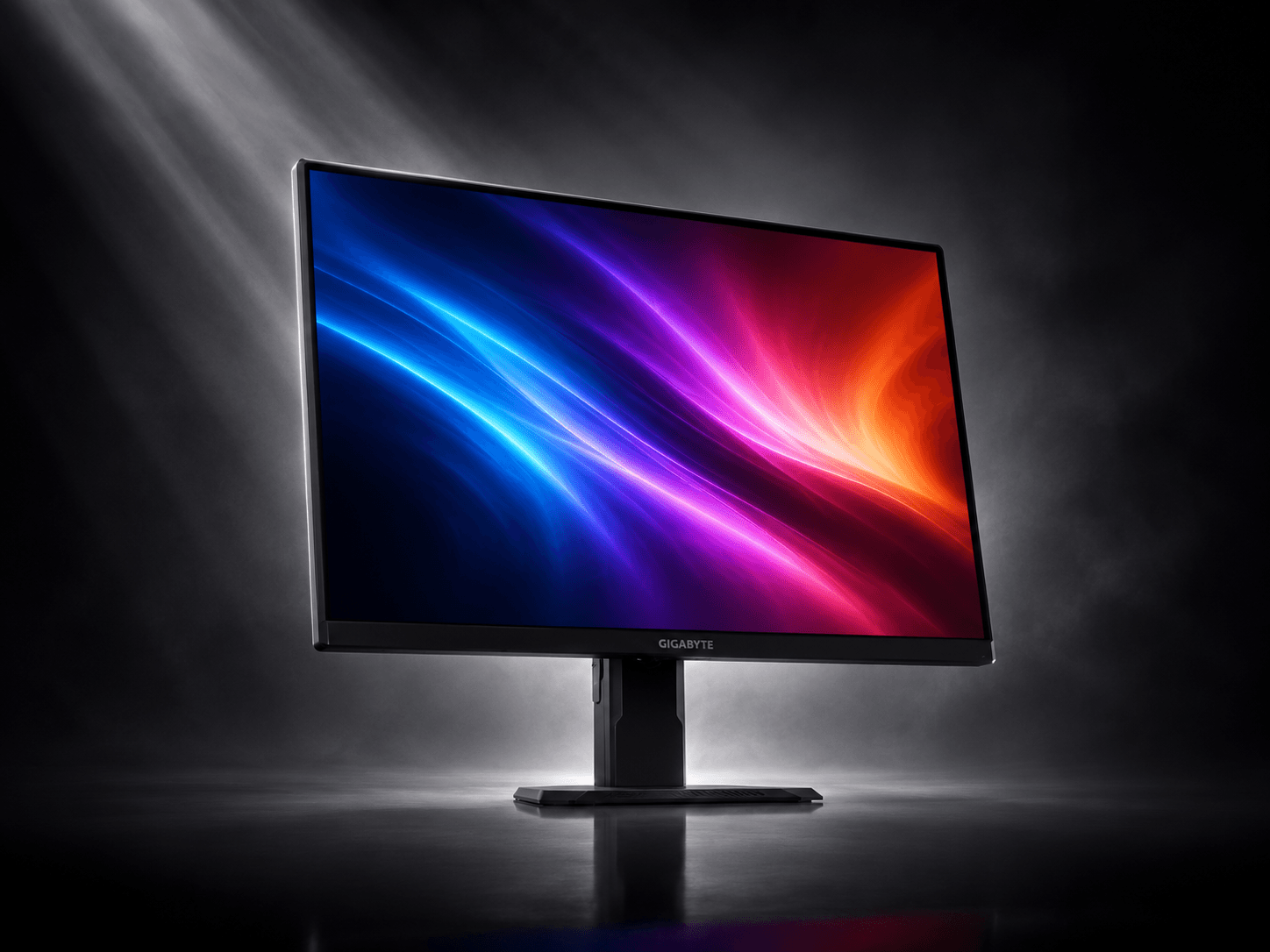 A Gigabyte GS27QA monitor on its stand, floating in a spotlit studio scene with an abstract wallpaper on the screen.