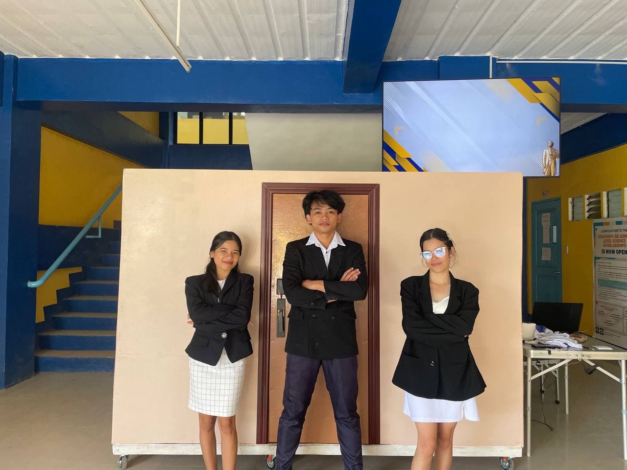 Final thesis prototype output showing the three student builders in front of the hotel-room model with the access-control door